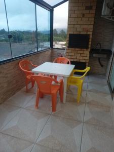 een tafel en stoelen in een kamer met ramen bij Apartamento completo praia do sonho in Palhoça