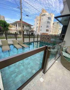 a balcony with a view of a swimming pool with chairs at Paraíso em Palmas com Piscina - 3 min do mar a pé! in Governador Celso Ramos