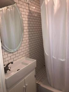 Baño blanco con lavabo y espejo en Skyline Siesta: Chic Couch Quarters in Heart of Echo Park – DTLA Awaits, en Los Ángeles