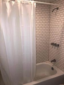 uma casa de banho com uma cortina de chuveiro branca e uma banheira em Skyline Siesta: Chic Couch Quarters in Heart of Echo Park – DTLA Awaits em Los Angeles