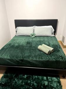 a bed with a green comforter and a book on it at Serene Living Downtown STL Loft in Saint Louis