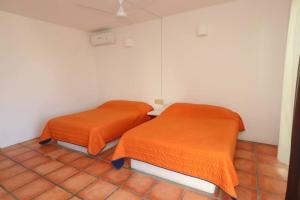 two beds in a room with orange sheets at Tehuana l House, Ocean view, pool. in Tangolunda