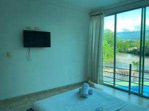 a bedroom with a bed and a large window at Hotel la cascada cristalina in Melgar