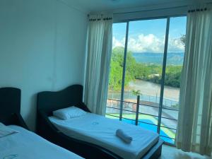 a bedroom with two beds and a large window at Hotel la cascada cristalina in Melgar