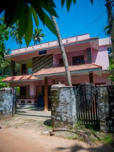 uma casa cor-de-rosa com uma vedação à frente. em Body Manthra em Varkala