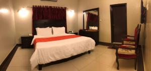 1 dormitorio con 1 cama grande y espejo en The Elet Business Hotel en Karachi