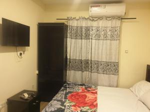 a bedroom with a bed and a window with a curtain at Joefad Home Stay - Wuse Zone 5 in Abuja