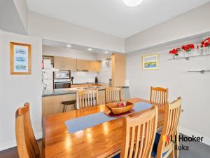 eine Küche und ein Esszimmer mit einem Holztisch und Stühlen in der Unterkunft Riverview Apartments 1 3 Building 1 Unit 3 in Iluka