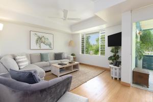 uma sala de estar com um sofá e uma televisão em Verandahs Boutique Apartments em Port Douglas