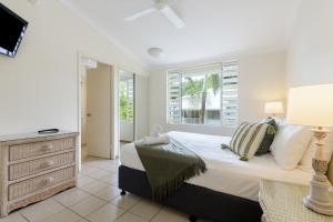 een slaapkamer met een bed, een dressoir en een raam bij Verandahs Boutique Apartments in Port Douglas