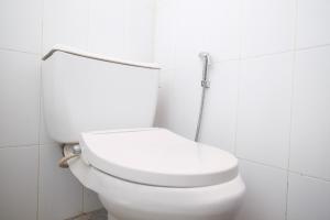 a white toilet in a white tiled bathroom at RedDoorz Syariah @ Jalan Dieng Wonosobo 2 in Garung