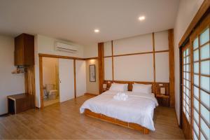 บ้านเรียวชิน น่าน りょうしん في نان: غرفة نوم بسرير كبير مع شراشف بيضاء
