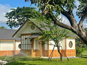 una casa con un árbol delante de ella en บ้านเรียวชิน น่าน りょうしん en Nan