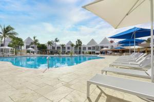 a swimming pool with lounge chairs and an umbrella at Courtyard by Marriott Aruba Resort in Palm-Eagle Beach