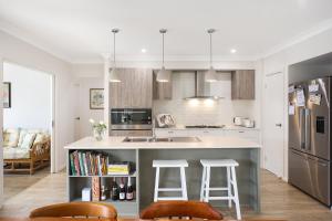 a kitchen with a counter and two bar stools at Waiheke Marina Getaway in Shellharbour