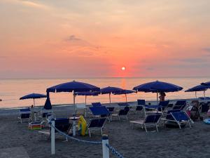 - un groupe de chaises longues et de parasols sur la plage dans l'établissement Parco La Bruca Villetta Margherita 800 mt dal mare, à Cipollina