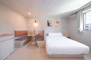 um pequeno quarto com uma cama e uma pequena mesa em Workers Hotel Ansan by AANK em Ansan
