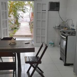 Il comprend une cuisine équipée d'une table, de chaises et d'une cuisinière. dans l'établissement Areia Branca / Casa 1/ casa 2, à Cabo Frio