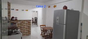 een keuken met een koelkast en een tafel. bij Areia Branca / Casa 1/ casa 2 in Cabo Frio