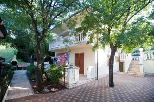 ein weißes Haus mit Bäumen davor in der Unterkunft Apartments Luka - free parking in Novi Vinodolski