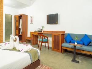 a bedroom with a bed and a couch and a desk at Tanei Angkor Resort and Spa in Siem Reap
