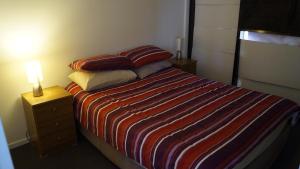 a bedroom with a bed with a striped blanket and a lamp at Smart apartment right in Canberra CBD in Canberra
