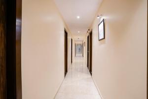 a hallway with white walls and white tile floors at FabExpress Wynd in Mumbai
