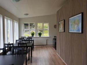 a dining room with tables and chairs and windows at Guesthouse Mikael in Höfn