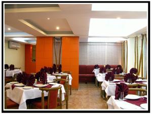 uma sala de jantar com mesas brancas e uma parede vermelha em HOTEL GOKUL em Gandhidham