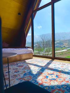 a room with a bed and a large window at Cabin Linggayoni dieng in Dieng