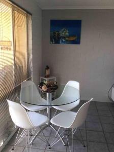 a dining room with a glass table and white chairs at Totally Beachin! - walking distance to the beach in Eden