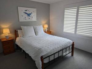 a bedroom with a bed and two night stands with lamps at Totally Beachin! - walking distance to the beach in Eden