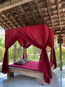 een bed met een rode luifel in een paviljoen bij Didu's Homestay Bed & Breakfast in Banyuwangi