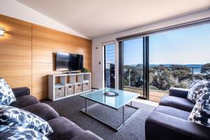 a living room with a couch and a tv and a glass table at Footprints 2 in Coles Bay