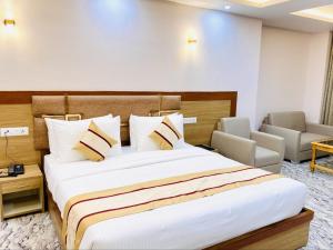 a hotel room with a large bed and chairs at Hotel Imolesh Imphal in Imphal