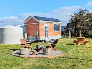 Yarra JunctionWarburton Tiny House - Tiny Stays的一座带两把椅子和火坑的小房子