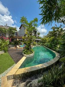 einen Pool inmitten eines Gartens in der Unterkunft Leafy Lofts Canggu in Canggu