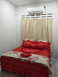 - une chambre avec un lit doté d'oreillers rouges et une fenêtre dans l'établissement Homestay Dahlia, à Teluk Intan