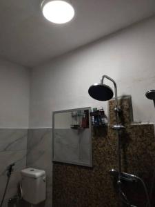 La salle de bains est pourvue d'une douche, de toilettes et d'une lumière. dans l'établissement Homestay Dahlia, à Teluk Intan