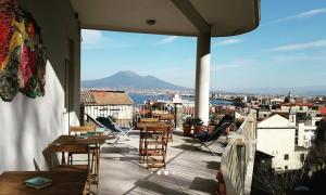 a balcony with tables and chairs and a view of the city at QuiSiSana a mare in Castellammare di Stabia