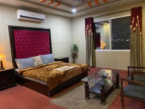 a bedroom with a large bed with a red headboard at Kashmir lodge in Muzaffarabad