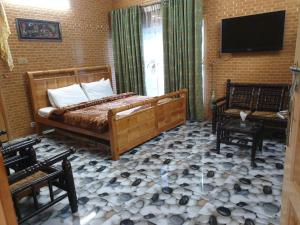 a bedroom with a bed and two chairs and a television at Kashmir lodge in Muzaffarabad