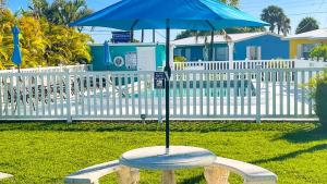 un parapluie bleu assis au-dessus d'un banc dans l'établissement Poolside King Cottage with Kitchen - 10 Minutes to Beach!, à Fort Myers