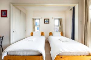 2 Betten in einem Zimmer mit 2 Fenstern in der Unterkunft Tenjin Minami San Ban Kan in Fukuoka