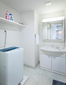 ein weißes Badezimmer mit einem Waschbecken und einem Spiegel in der Unterkunft Tenjin Minami San Ban Kan in Fukuoka