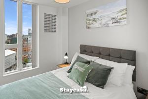 a bedroom with a bed with pillows and a window at Spectacular Apartment Balcony View In City Centre in Manchester