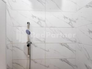 a shower with white marble walls and a shower head at Ada Guest House Medan Redpartner in Medan