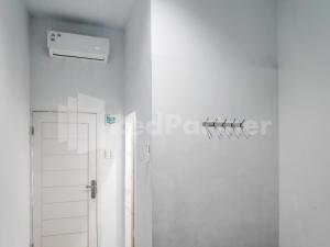 Cette chambre blanche dispose d'une douche et d'une porte. dans l'établissement Ada Guest House Medan Redpartner, à Medan