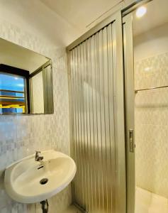 een badkamer met een wastafel, een spiegel en een douche bij Frutta Hostel in Patong Beach
