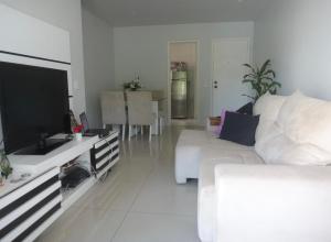 uma sala de estar branca com um sofá branco e uma televisão em Apartamento Área Nobre no Recreio dos Bandeirantes no Rio de Janeiro